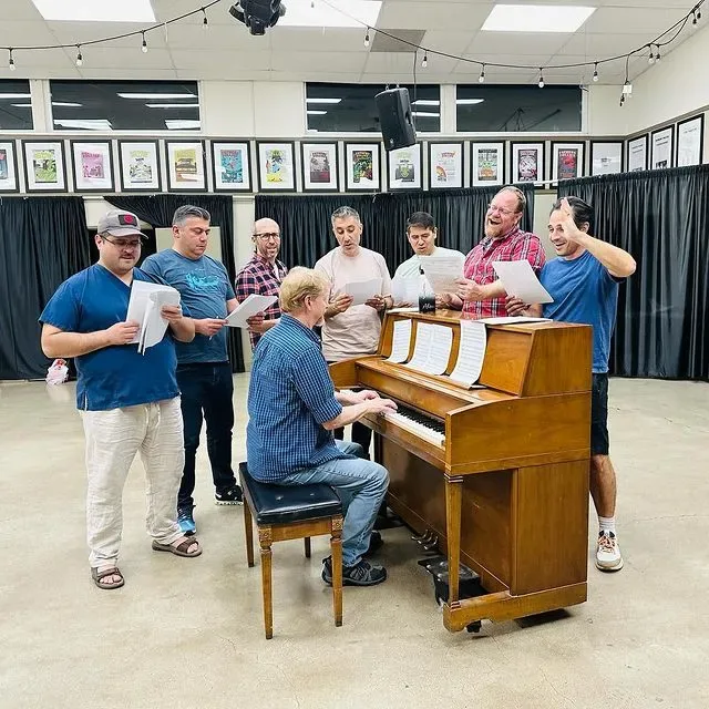 Dads singing together around the piano at the clubhouse